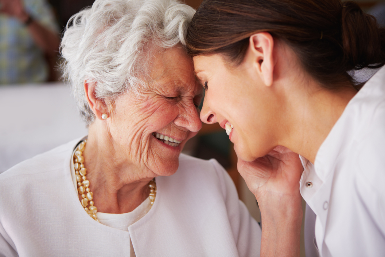elderly woman touching face of young female nurse